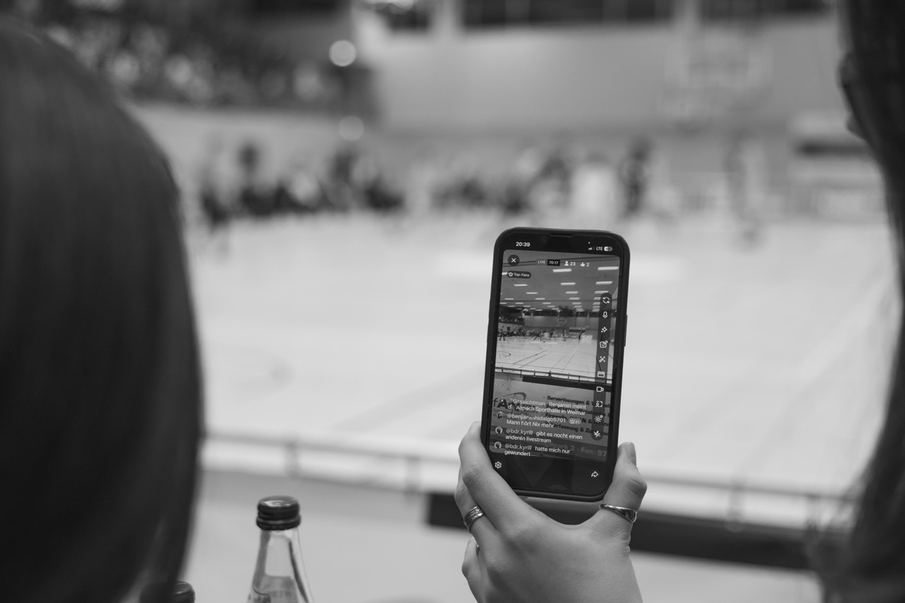 Frau mache eine Instagram-Story von Piranhas Basketball Spiel